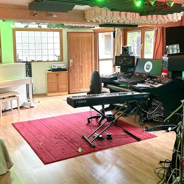La control room du studio : console de mixage, écoutes de proximité, claviers et batterie